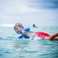 Фото мальчик серфер гребет на лайнап в русском серф кемпе Endless Summer